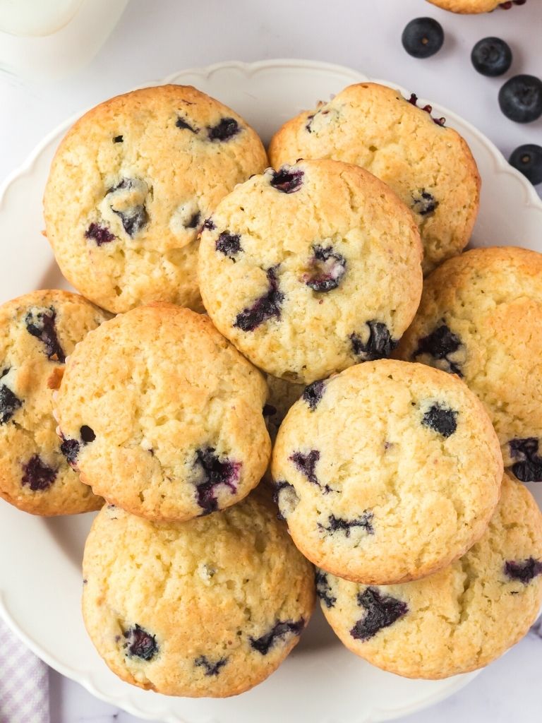 White plate of muffins with blueberries in them stacked together. 