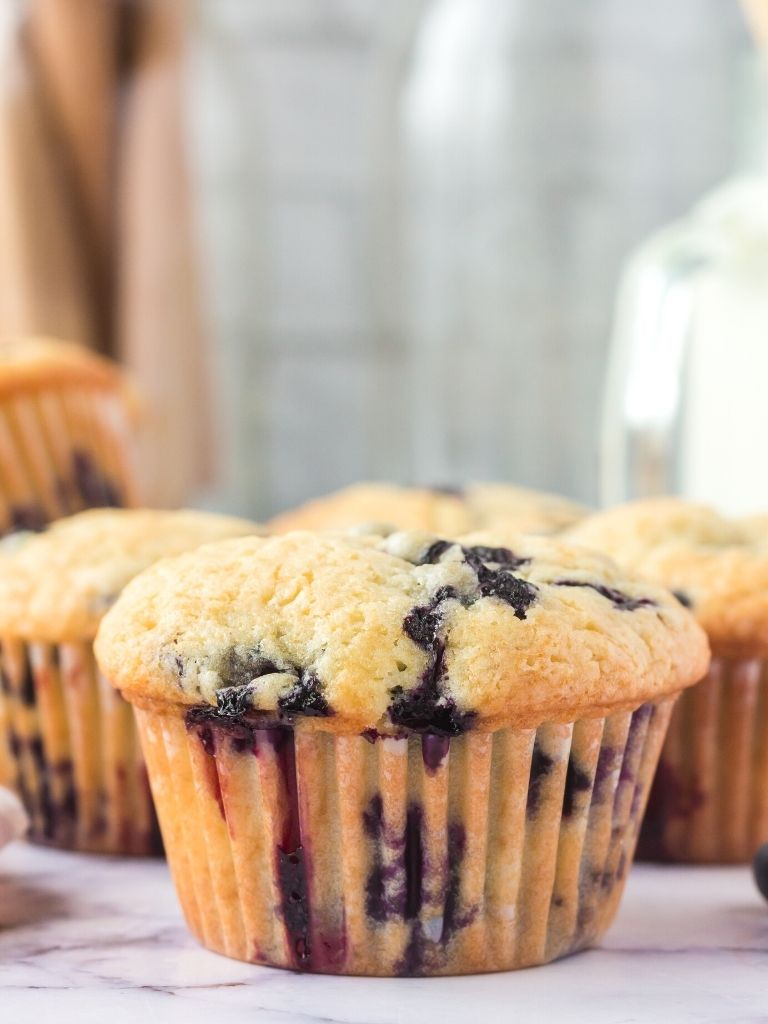 Muffin in a liner with fresh blueberries in it.