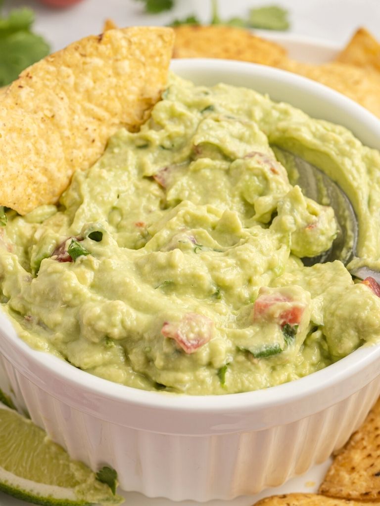 A bowl with guacamole in it and a spoon.