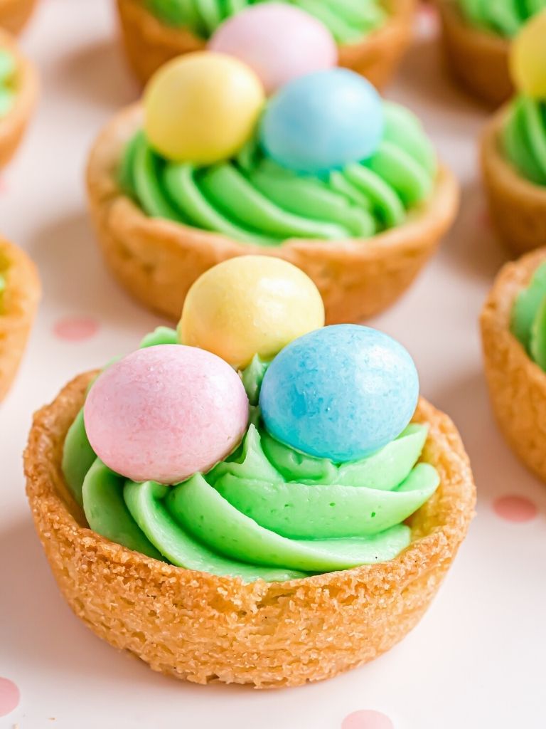 Close up shot of a sugar cookie cups with frosting and chocolate egg on top.