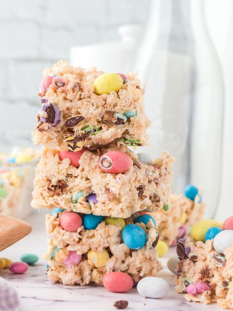 Stack of krispy treats for easter with a white background and candy pieces on it. 