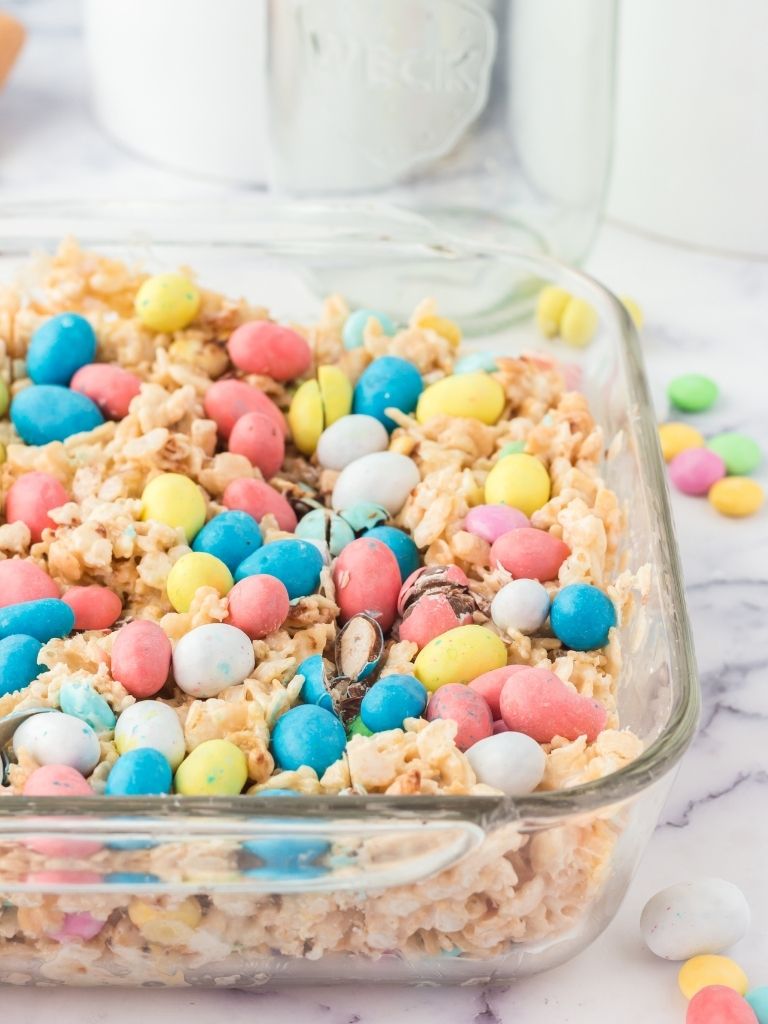 A pan of rice krispy treats in a glass pan and topped with candy.