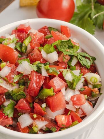 Salsa inside a bowl with tomatoes, cilantro, and onion.