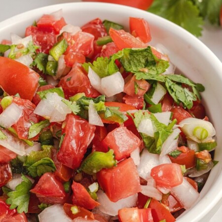 Salsa inside a bowl with tomatoes, cilantro, and onion.