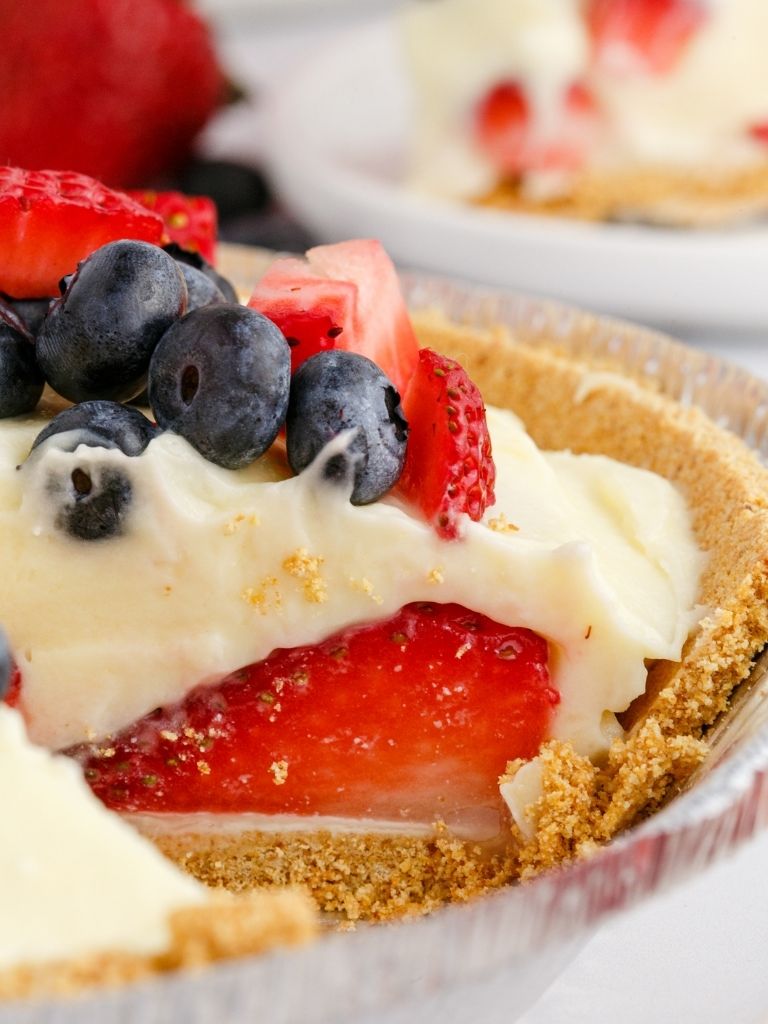 A close up shot of the inside of the pie with strawberries and other berries inside a graham cracker crust.