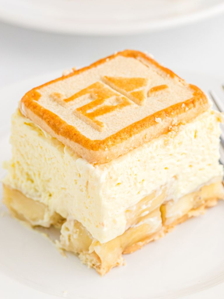 Square of banana dessert with a cookie on top and a pudding layer.