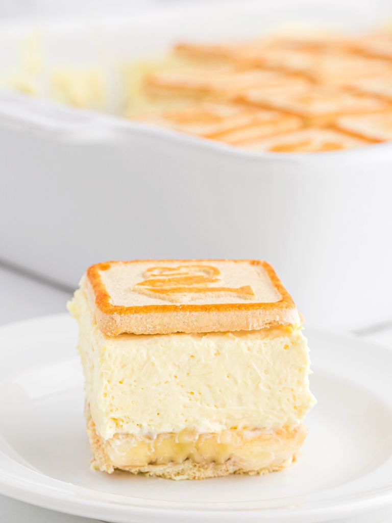 A square of banana pudding dessert on a white plate.