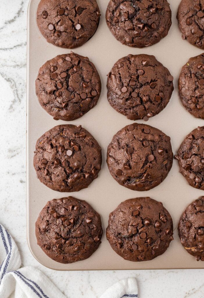 A muffin tin with baked zucchini muffins in it. 