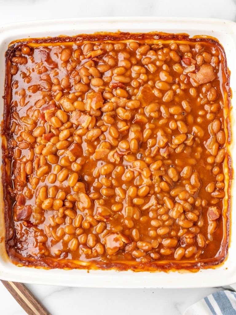 A pan of baked beans with a serving spoon to the side of them.