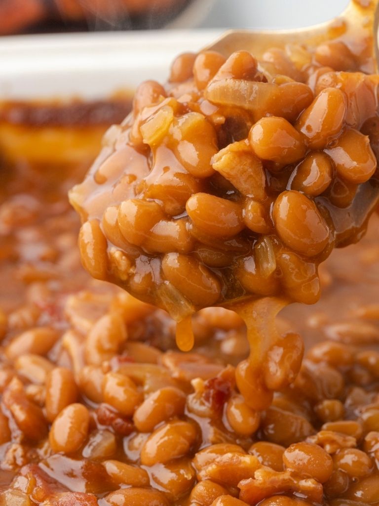 A close up shot of a scoop of baked beans on a spoon.