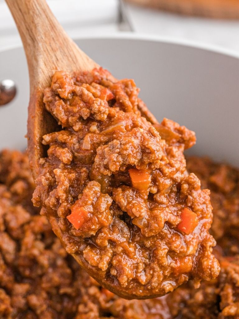 A wooden spoon with a serving of sloppy Joe ground beef mixture on it. 