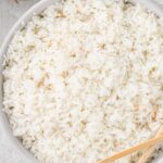 Overhead shot of coconut rice recipe inside a white bowl with wooden chopsticks to the side.