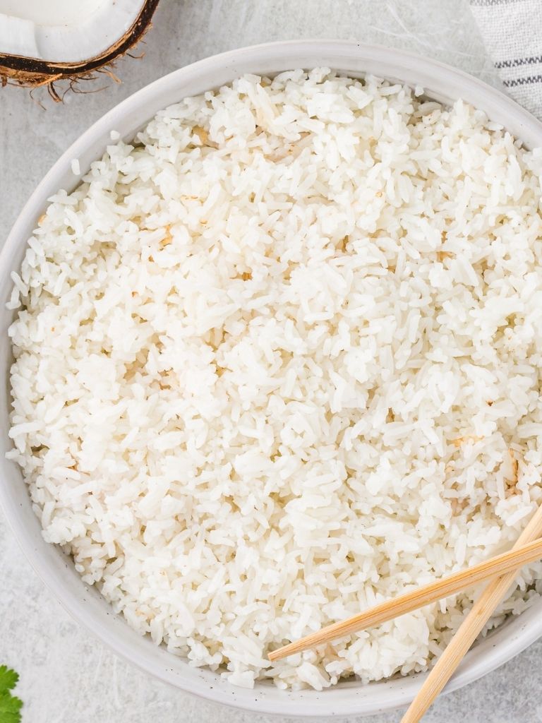 Overhead shot of coconut rice recipe inside a white bowl with wooden chopsticks to the side. 