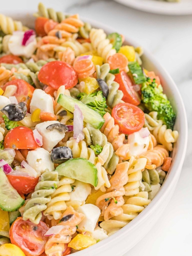A bowl with pasta salad inside of it against a white background.
