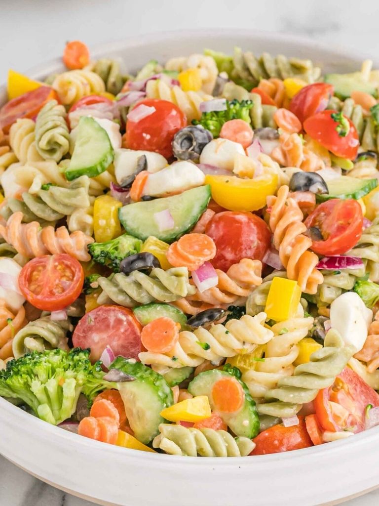 A bowl with tri color rotini pasta salad inside of it. 