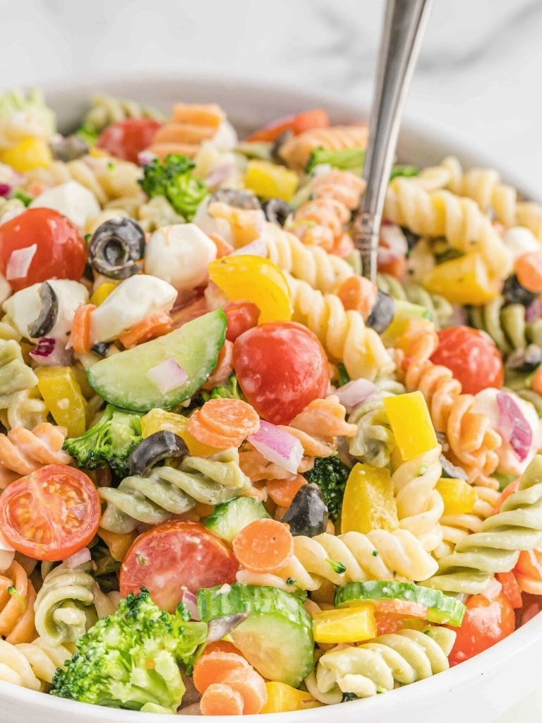 Pasta salad with a silver spoon in it.