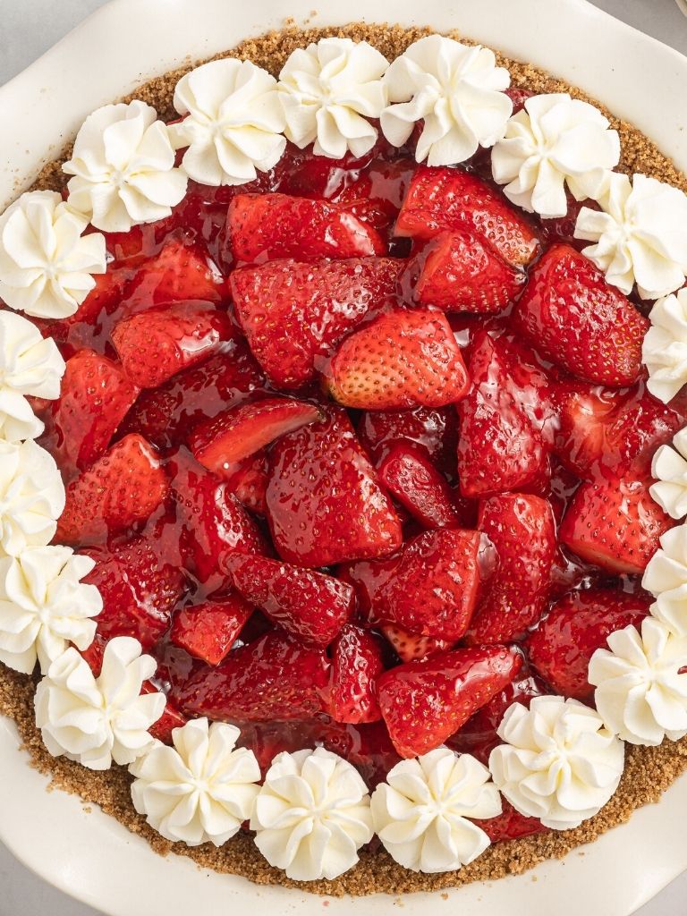 A strawberry pie inside a pie plate with a graham cracker crust. 