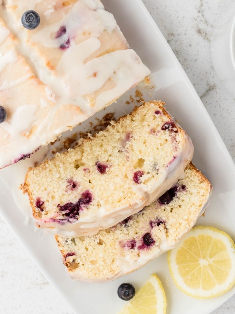 A loaf of lemon blueberry bread with some slices cut to show the inside of the quick bread.