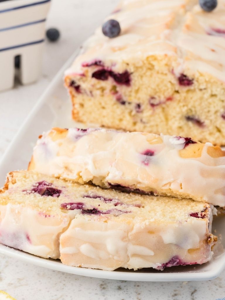 A close up of some slices of lemon blueberry banana bread that is sitting on a white plate. 