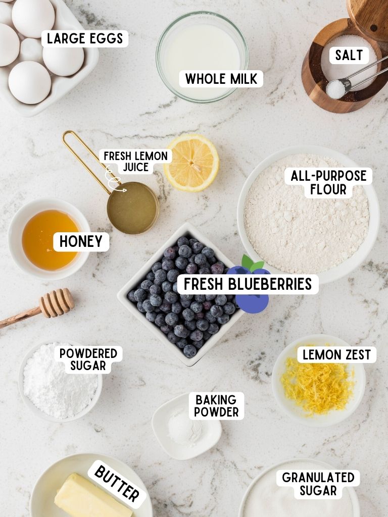 Ingredients needed to make quick bread with lemon and blueberries. Each ingredient is labeled in black text with what it is. 