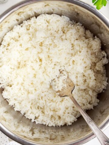 White rice inside an instant pot with a silver fork inside the rice.