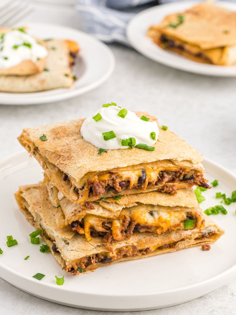 Stack of baked quesadillas on a white plate.