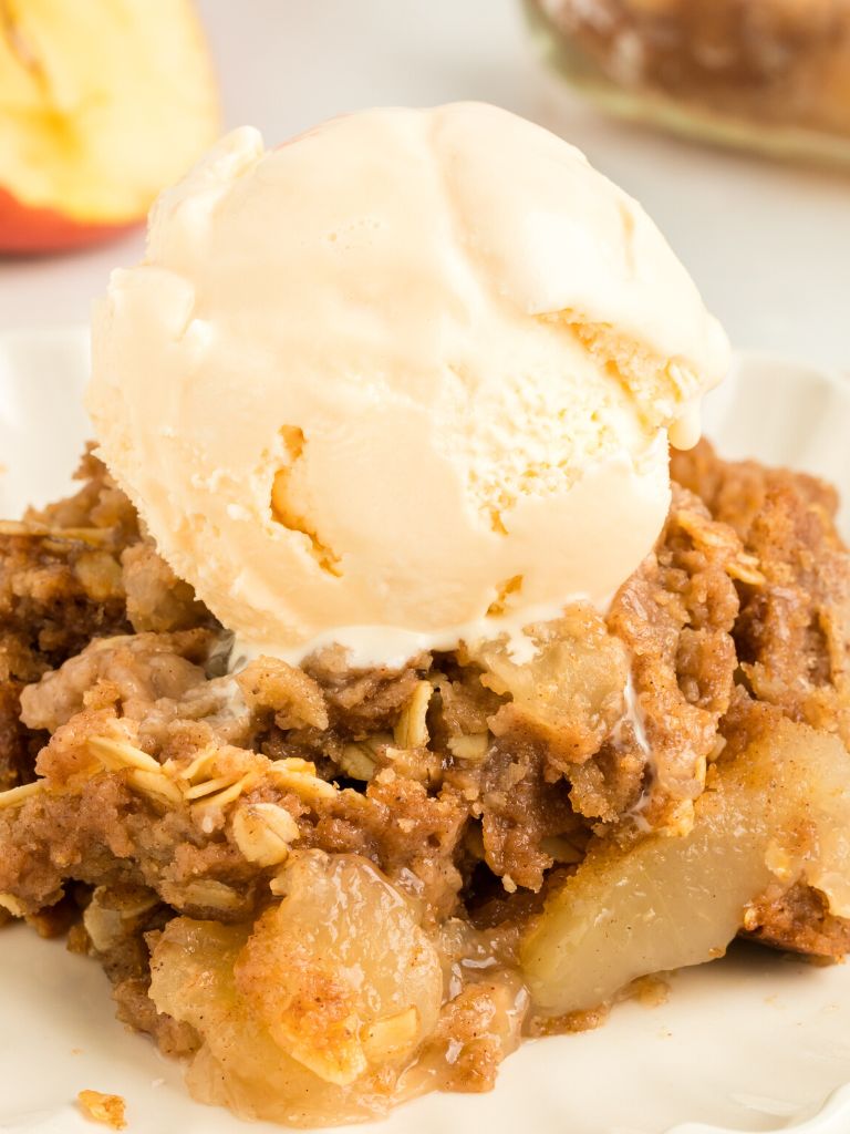 Apple crisp dump cake on a white plate with ice cream on top. 