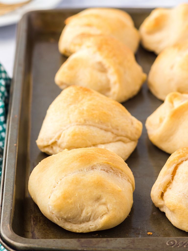 A tray of crescent dough pillows on a cookie sheet.