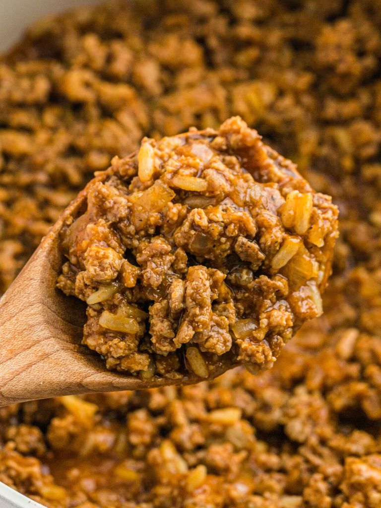 A wooden scoop with ground meat mixture inside of it. Close up shot to show the texture of the meat mix.