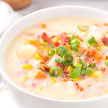 A white bowl of chowder soup with a potato in the background and a side angle view of the bowl of chowder.