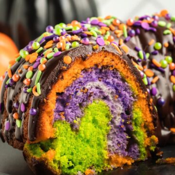 A side view of the inside of a Bundt Cake with swirls of halloween colors in the middle.