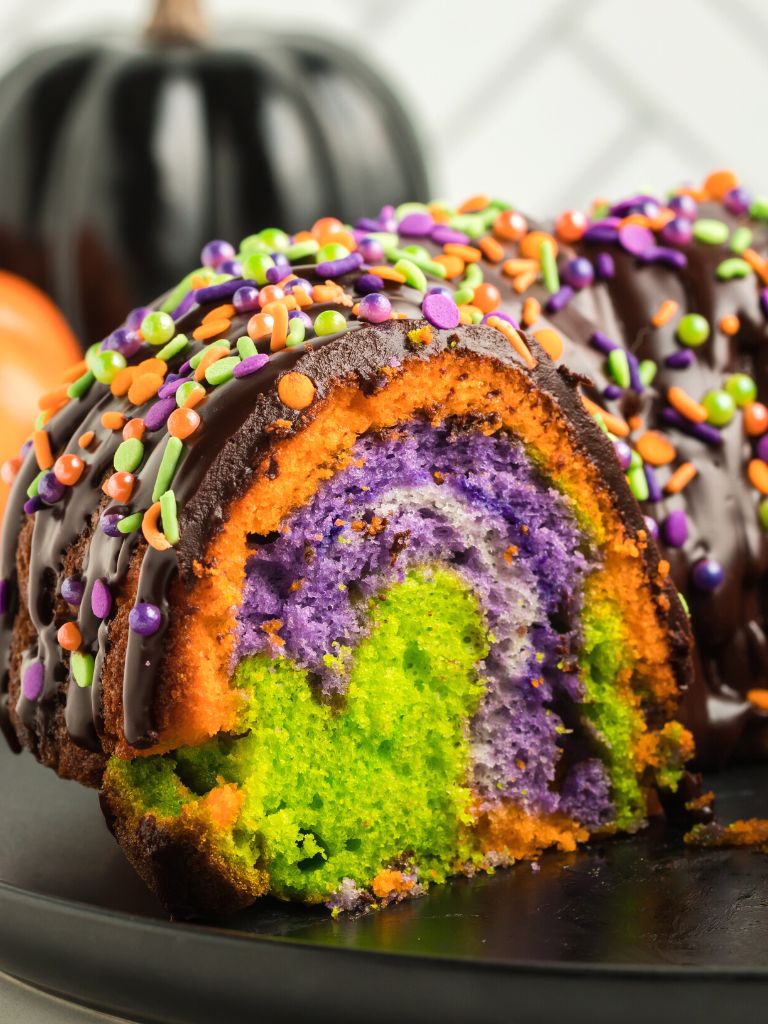 A side view of the inside of a Bundt Cake with swirls of halloween colors in the middle. 