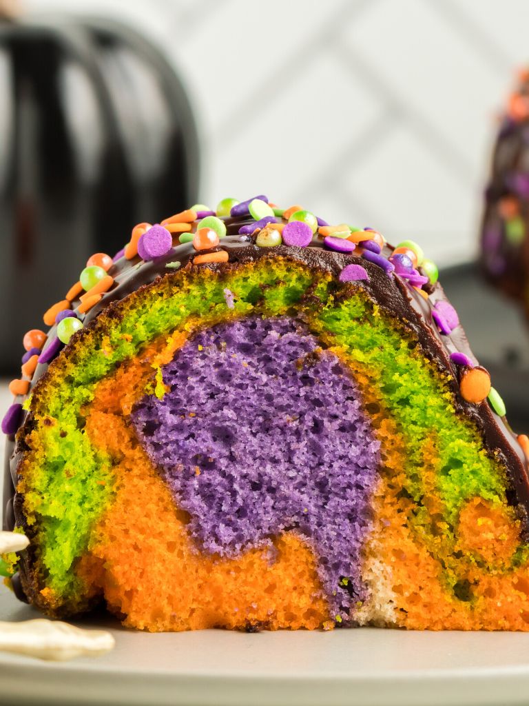 A slice of cake with swirls of halloween color inside the cake. 