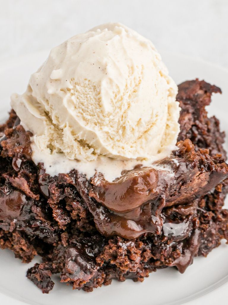 A serving of chocolate cake topped with fudge sauce and ice cream.