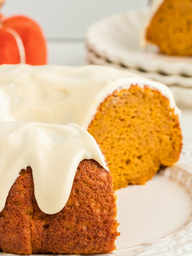 A bundt cake frosted sitting on a white serving plate.