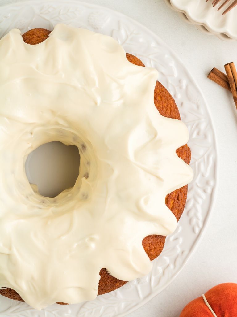 Overhead picture of a bundt cake topped with frosting sitting on a white plate. 