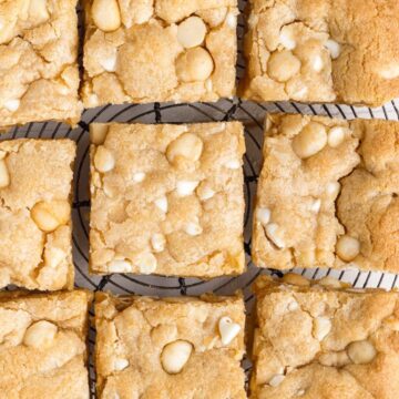 Overhead shot of cookie bars on a wire rack with white chocolate chips and macadamia nuts.