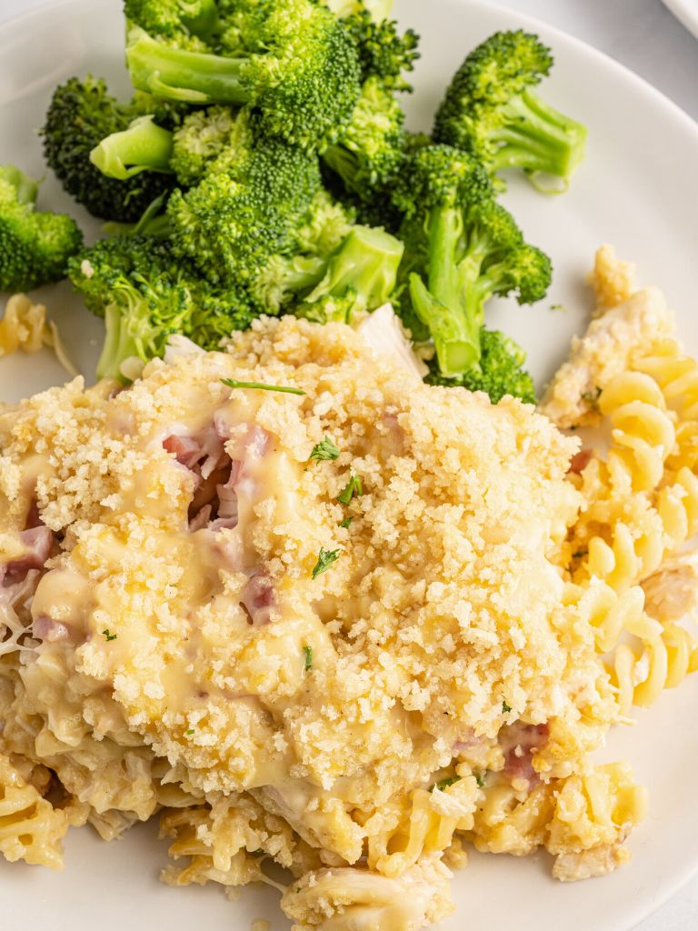 A white plate with dinner on it, a casserole main dish and a side dish of broccoli. 
