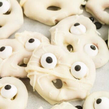 A pile of white chocolate covered pretzels with candy eyeballs for halloween treat.