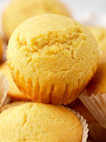 cornbread muffins inside a basket lined with a white towel.