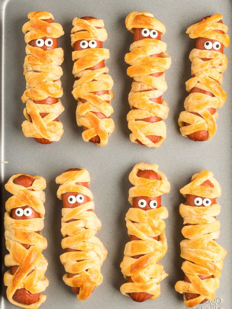 Tray of hot dogs made to look like mummies for halloween.