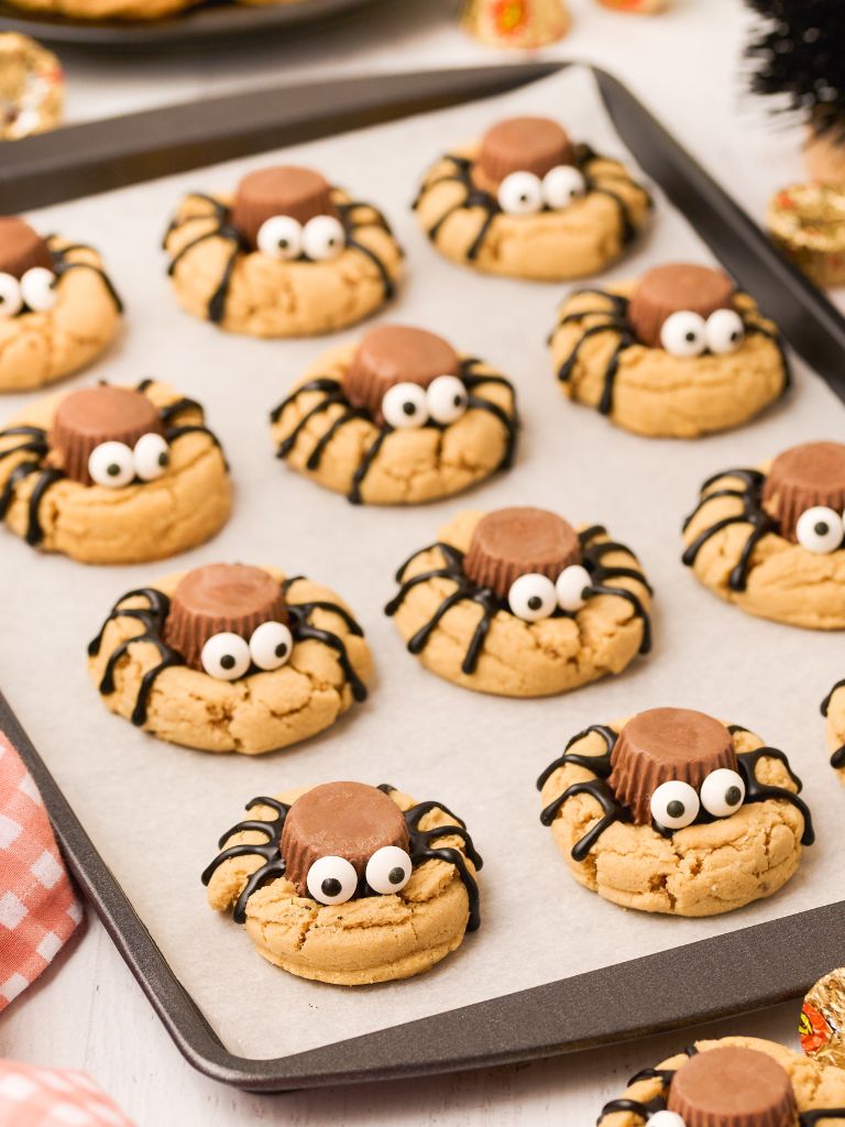 A cookie sheet of spider looking cookies sitting on top of parchment paper.