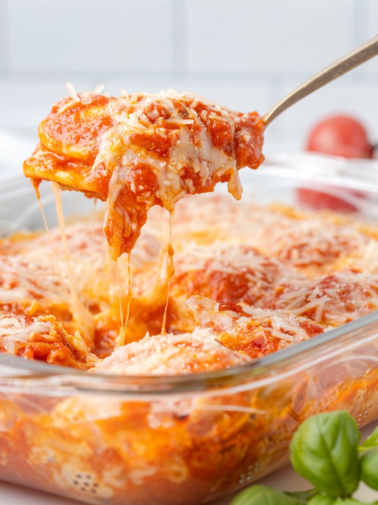 A cheese pull of pasta and cheese over a baking dish of casserole.
