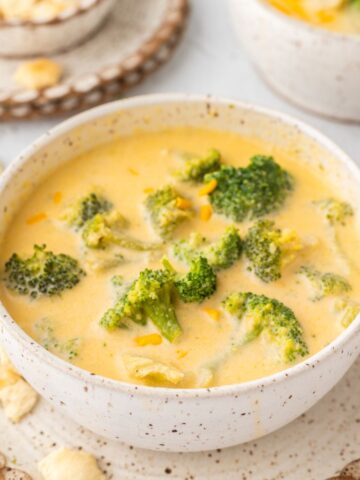 A bowl of soup with broccoli and cheddar cheese.