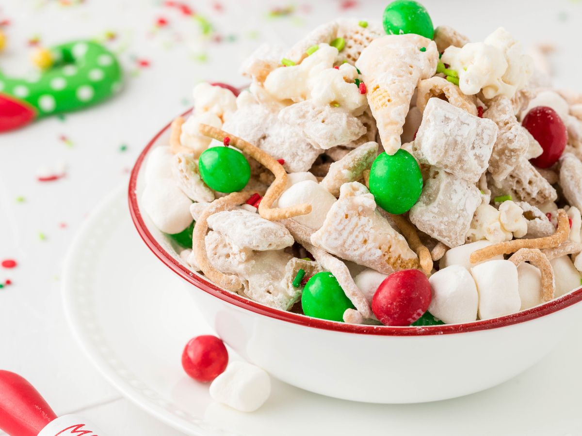 A bowl of snack mix with christmas colors in the background. 