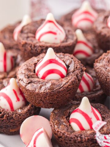 Stacks of brownie bites with a kiss on top, with some unwrapped kisses next to them.