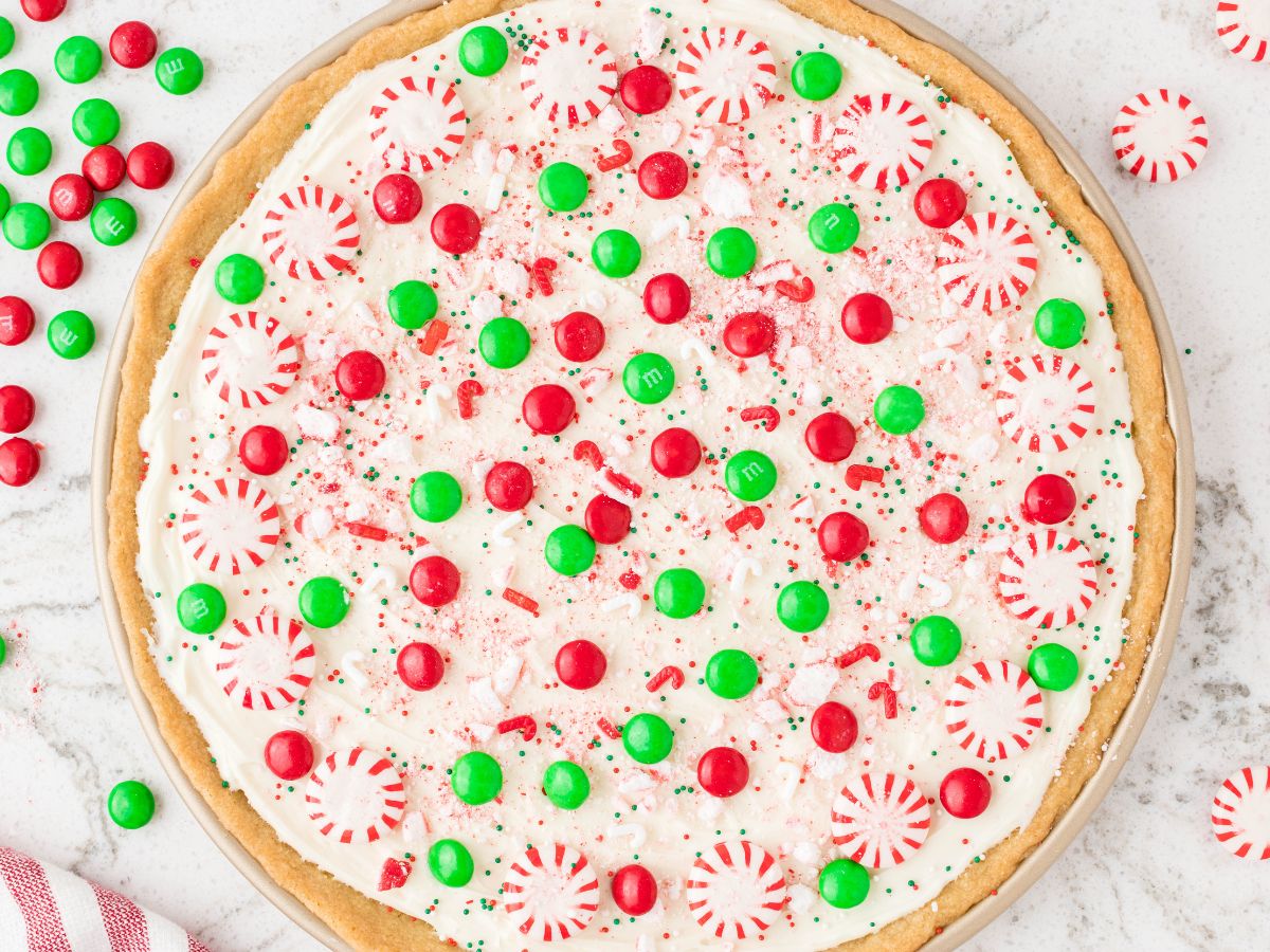 Horizontal photo of a dessert pizza with red and green decorations on it. 