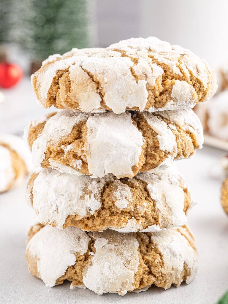 A stack of crinkle cookies with decorative Christmas items in the background. 