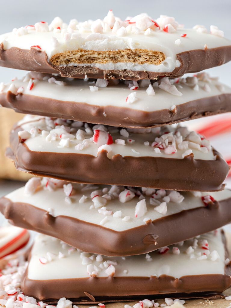 Stack of peppermint bark crackers with a bite out of the top one. 