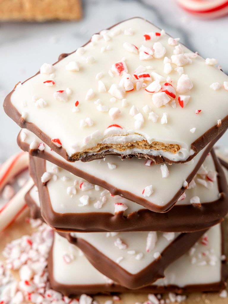 Stack of chocolate covered crackers topped with candy cane pieces. 